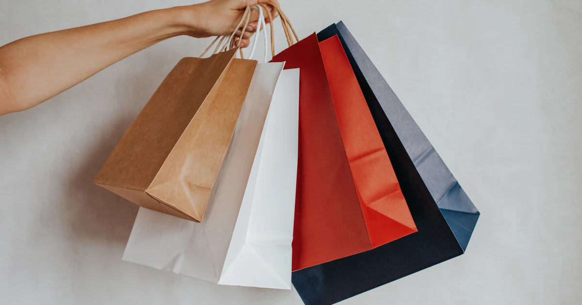 Mano che tiene borse della spesa colorate, simbolo del comportamento d'acquisto