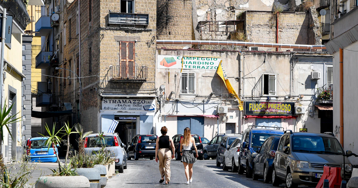 Una via stretta con negozi diversi, ognuno con la sua identità locale, esempio di autonomia che convive con la coerenza