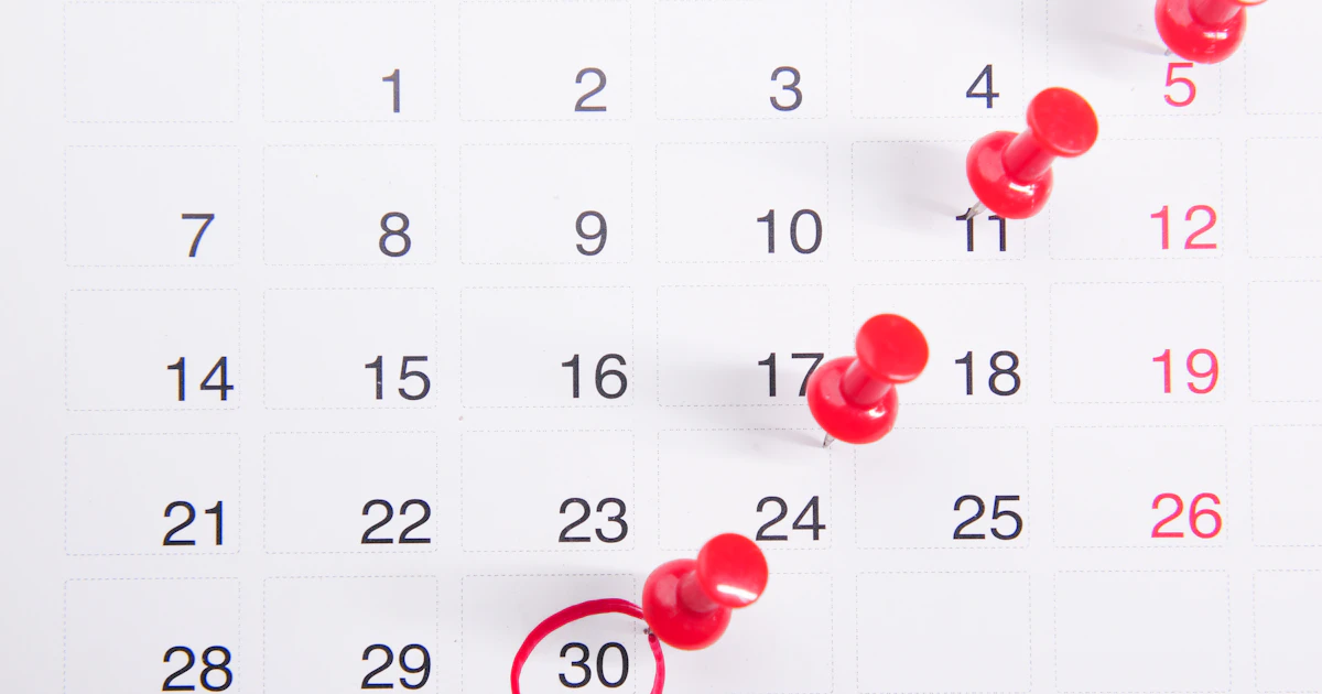 Calendario cartaceo con piccole puntine rosse su date selezionate