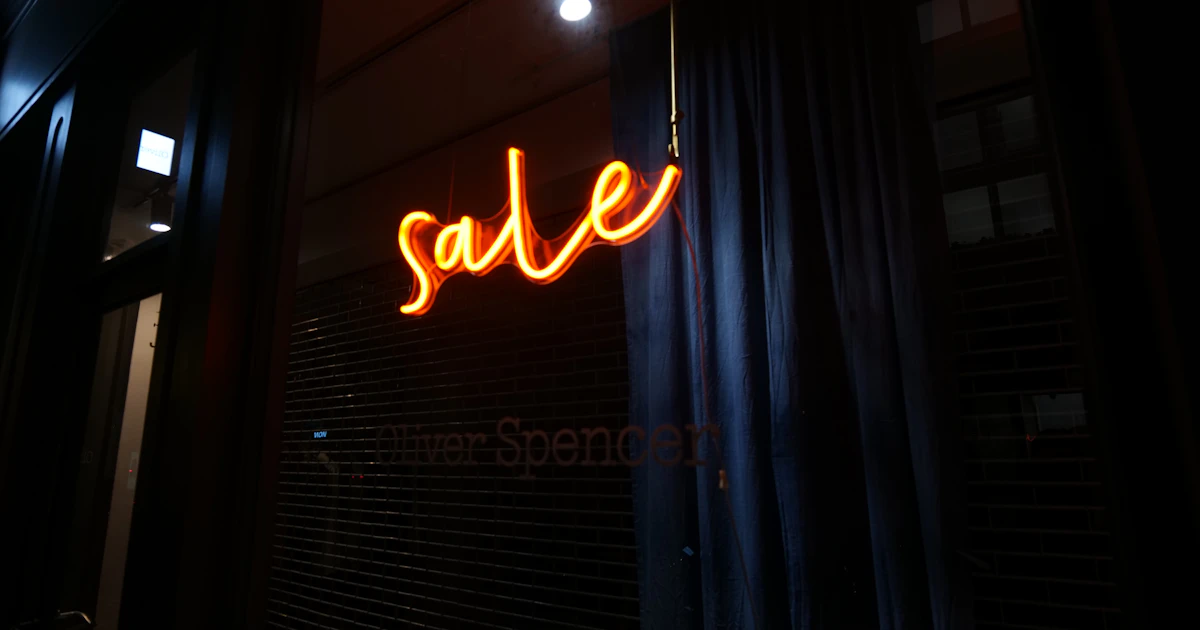 Insegna luminosa SALE arancione vista attraverso vetrina nera