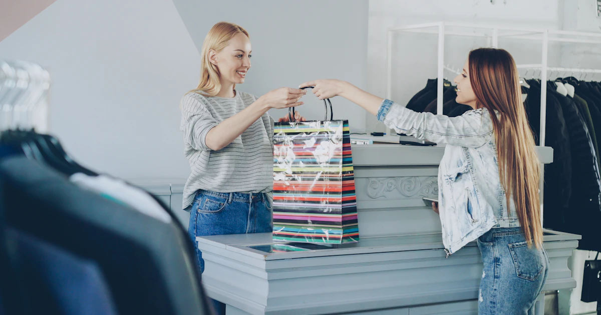 Cliente felice riceve la borsa con gli acquisti dalla commessa al banco cassa