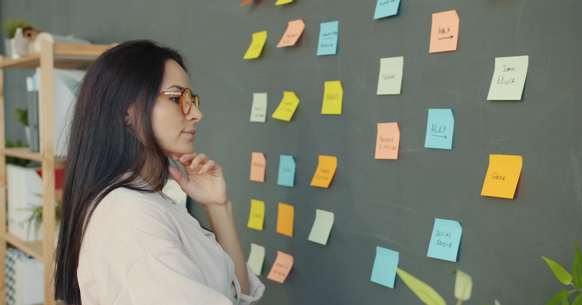 Una manager guarda decine di post-it colorati attaccati al muro, sopraffatta dal volume di informazioni