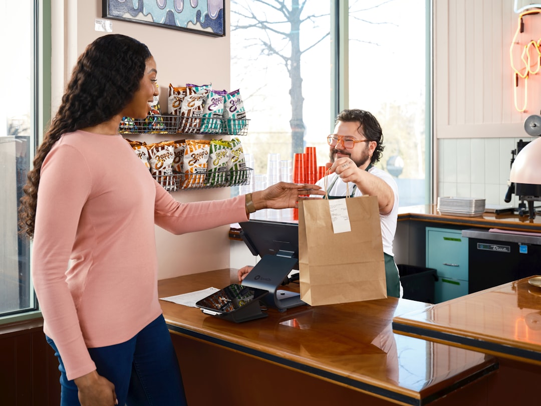 Commessa che consegna un acquisto a una cliente al bancone del negozio